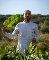 Uomo con camice bianco tiene una grande foglia in un campo verde.