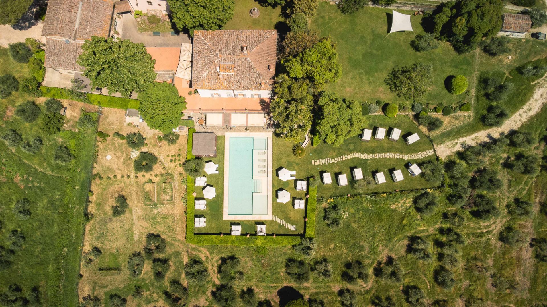 Vista aerea di una villa con piscina e giardino ben curato.
