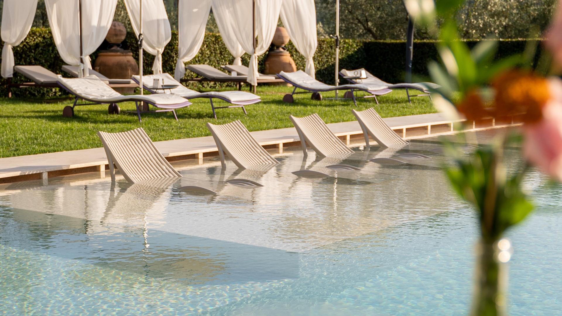 Piscina elegante con lettini e tende bianche, atmosfera rilassante e lussuosa.