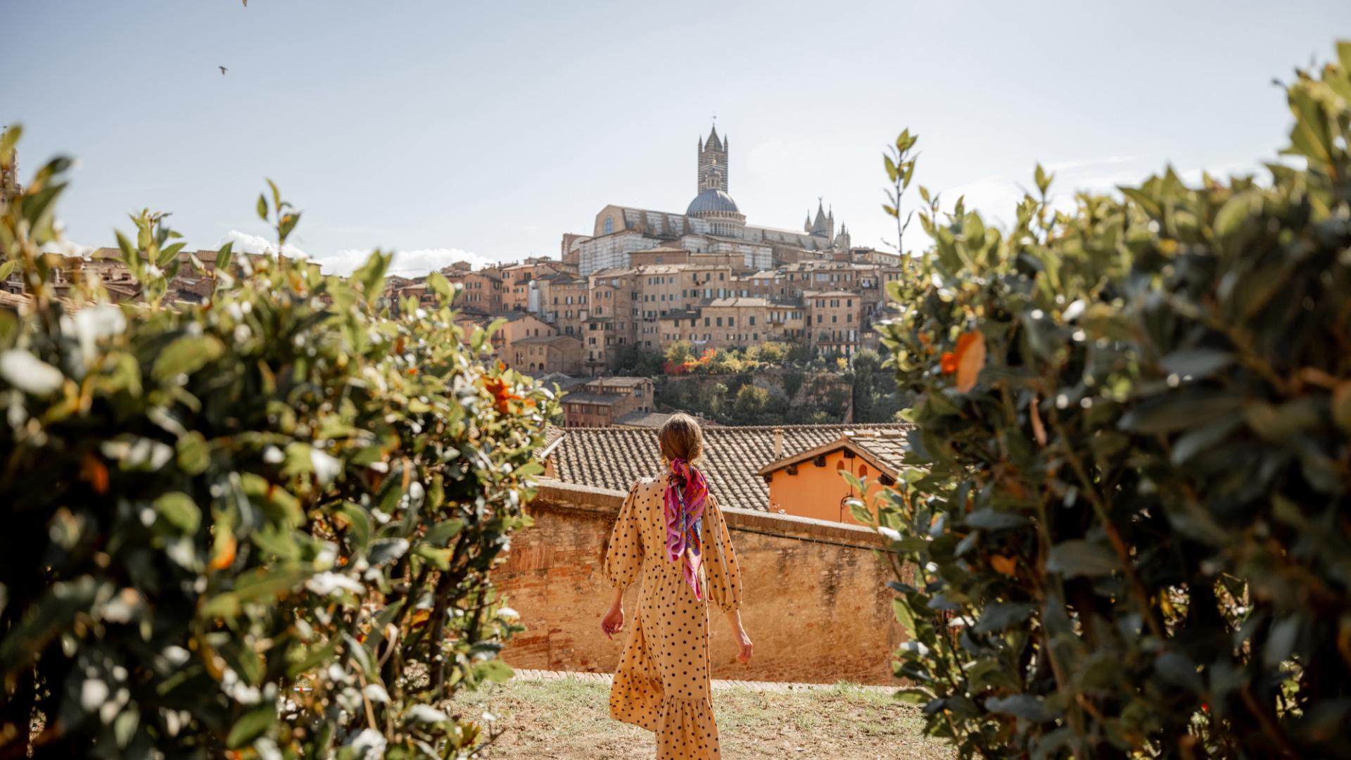 Donna in abito a pois guarda la città storica con cattedrale sullo sfondo.