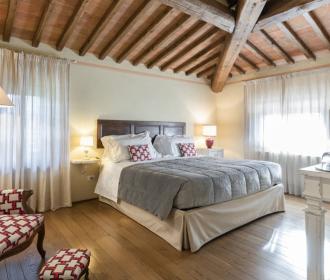 Camera da letto elegante con travi a vista e arredi classici.