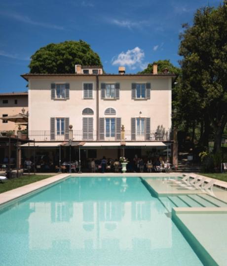 Villa elegante con piscina, circondata da alberi e cielo azzurro limpido.