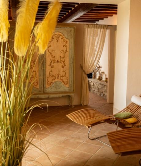 Interno accogliente con chaise longue, armadio decorato e tende trasparenti.
