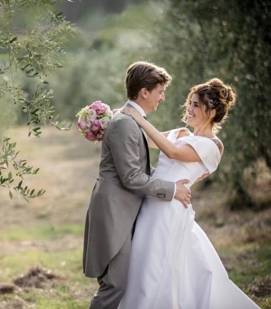 Coppia di sposi felici in un abbraccio romantico all'aperto con bouquet di fiori.