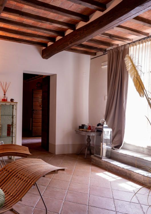 Soggiorno accogliente con arredi in legno, piante decorative e soffitto con travi a vista.
