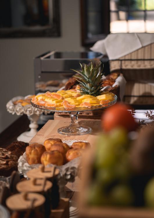 Buffet con frutta fresca, dolci e pane su un tavolo elegante.