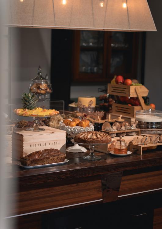 Buffet con dolci, frutta e pane su un tavolo di legno elegante.