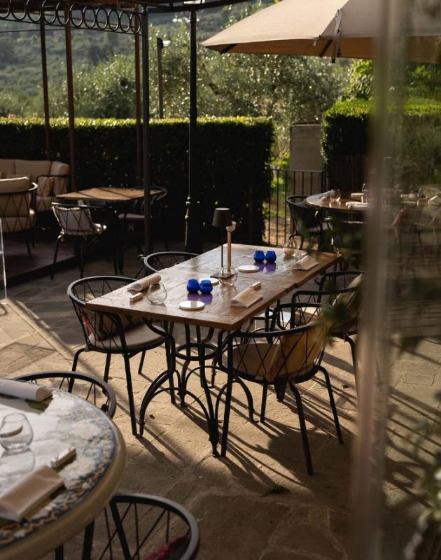 Ristorante all'aperto elegante con tavoli apparecchiati, ombrelloni e vista sulla natura.