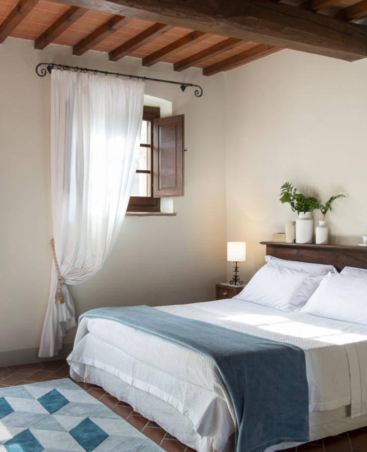 Bright room with cozy bed, exposed beams, and garden view.